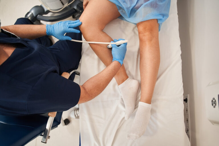 Doctor performing an ultrasound examination of a patient's leg veins