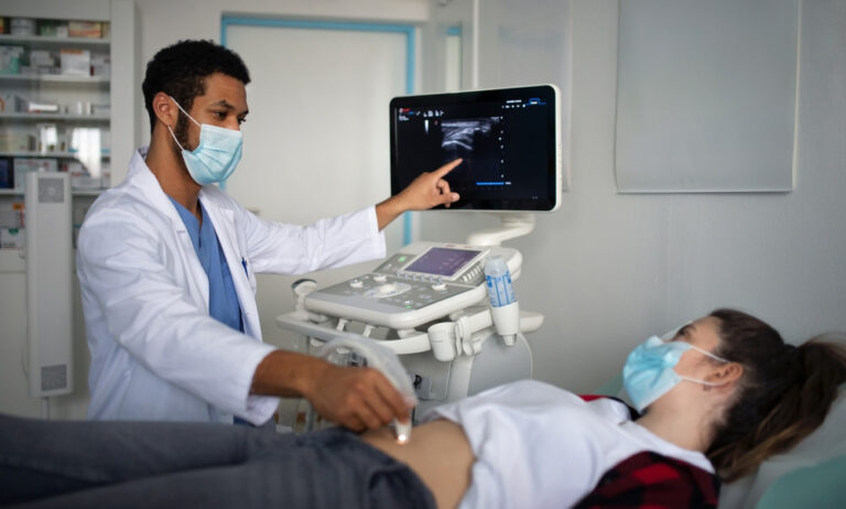 Young doctor examining a young woman using ultrasound equipment in clinic