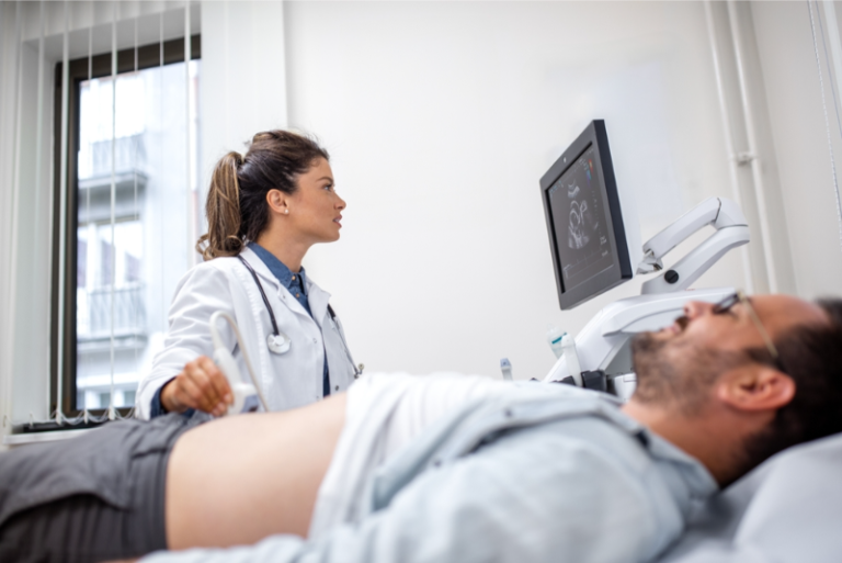 Female doctor performing an abdominal ultrasound on a male patient while checking the results on screen